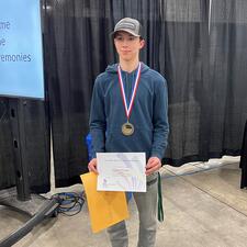 Male gold medalist stands with award